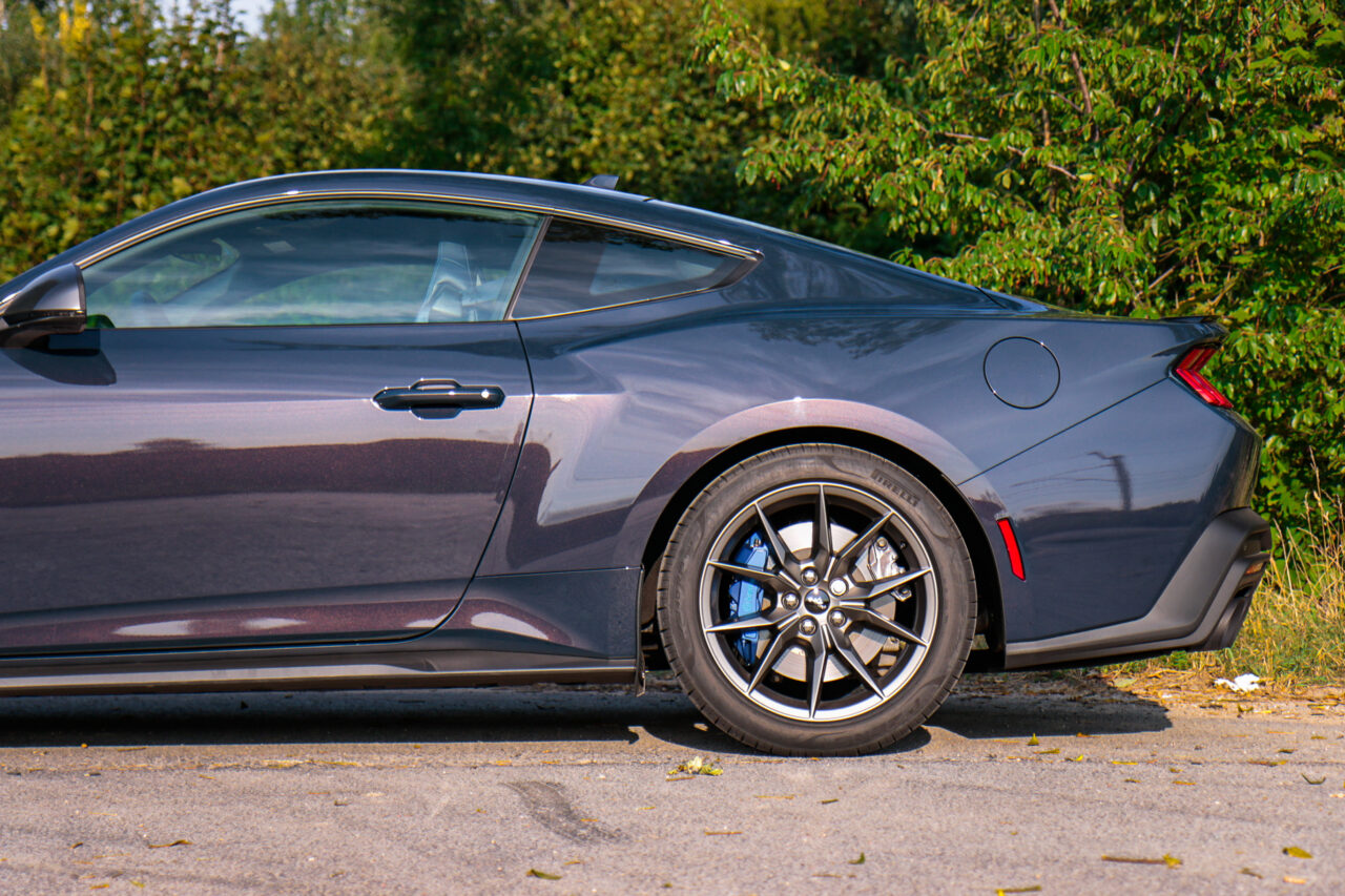 Test Ford Mustang Dark Horse, widok boczny samochodu na tle zieleni.