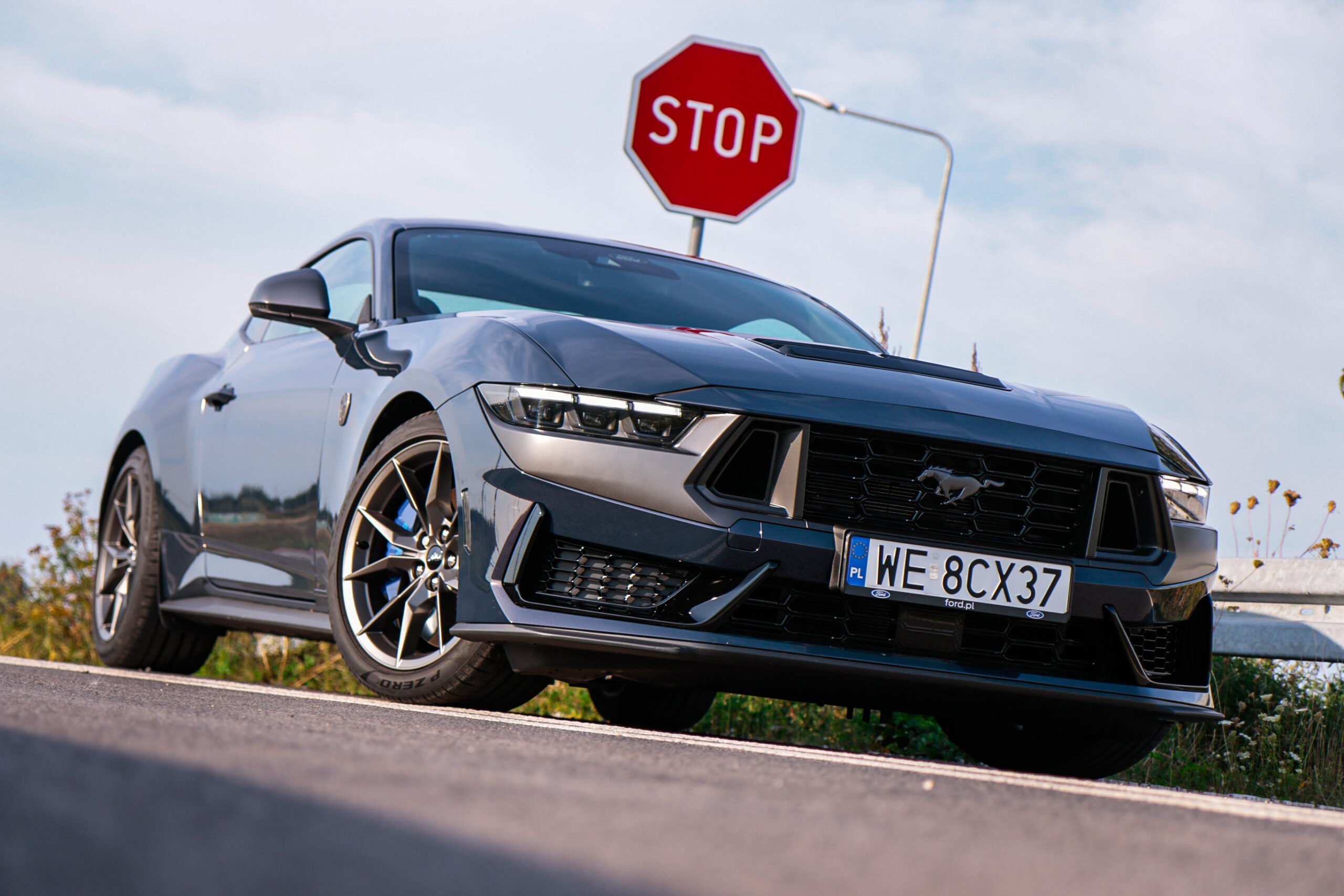 Test Ford Mustang Dark Horse stojącego na drodze przed znakiem stop.