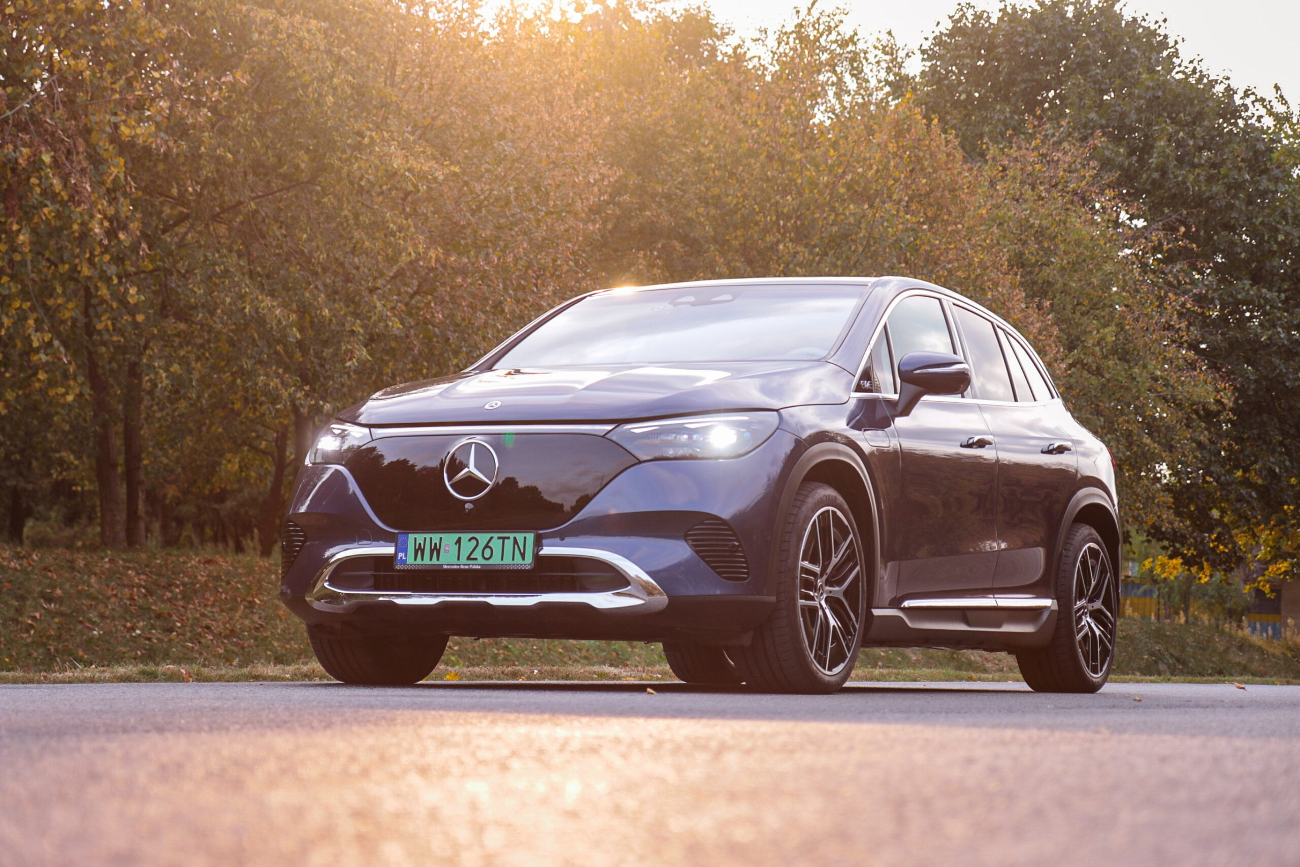 Mercedes EQE SUV 500 4MATIC na tle drzew i zachodzącego słońca.