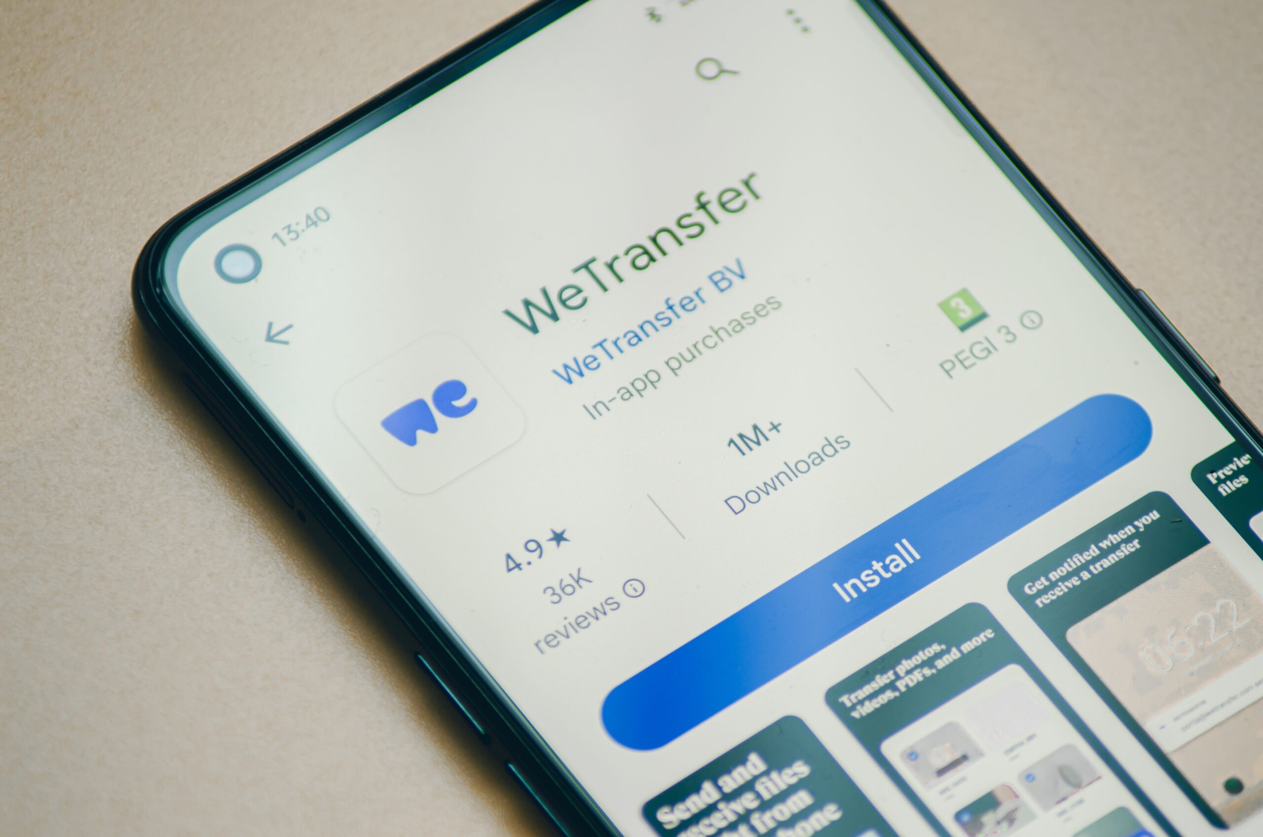 Ekran smartfona z aplikacją WeTransfer w sklepie Google Play, przyciskiem "Zainstaluj" i szczegółami, takimi jak liczba pobrań i oceny.