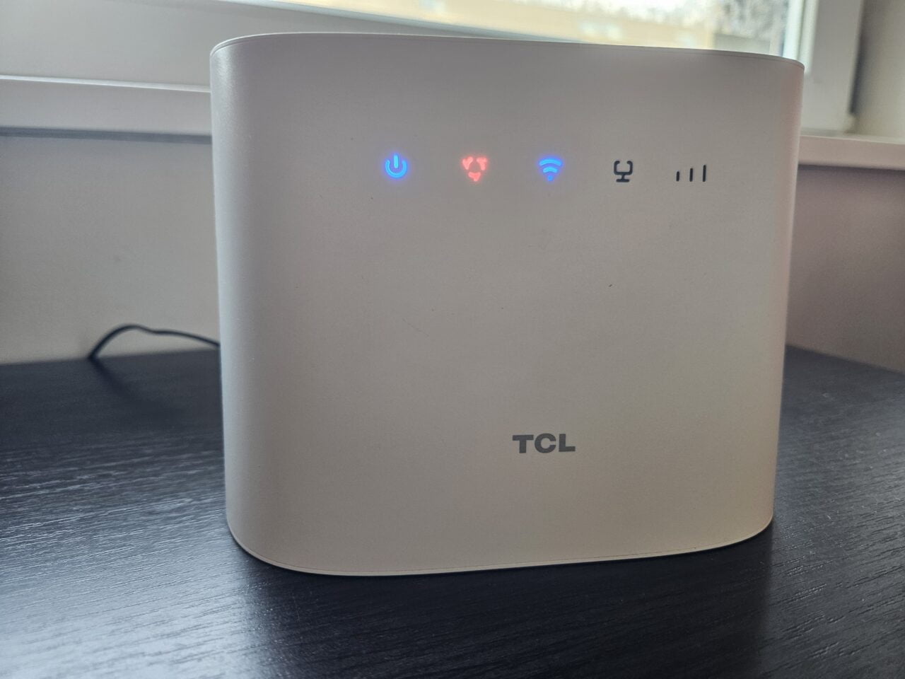 biały router TCL stojący na stole