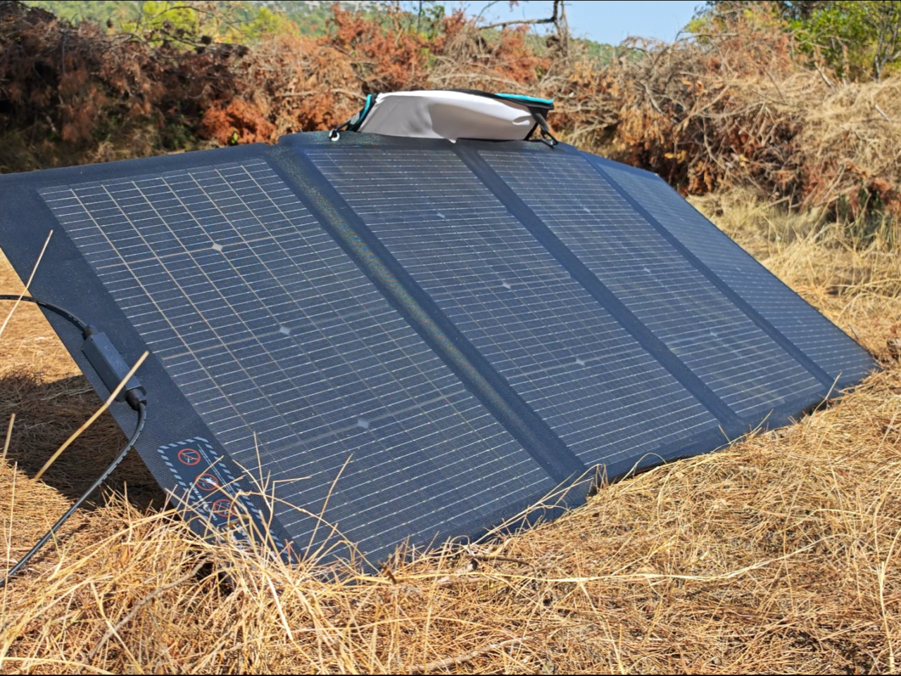 Przenośny panel słoneczny na suchej trawie w plenerze. Stacja zasilania i panele solarne Ecoflow