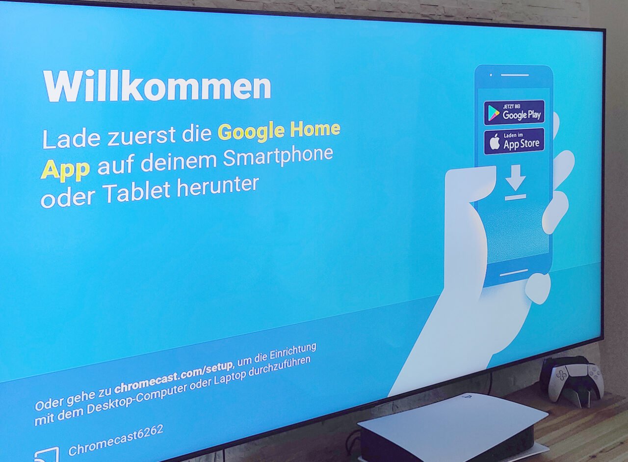 Ekran telewizora z napisem "Willkommen" i instrukcjami dotyczącymi pobrania aplikacji Google Home na smartfon lub tablet.