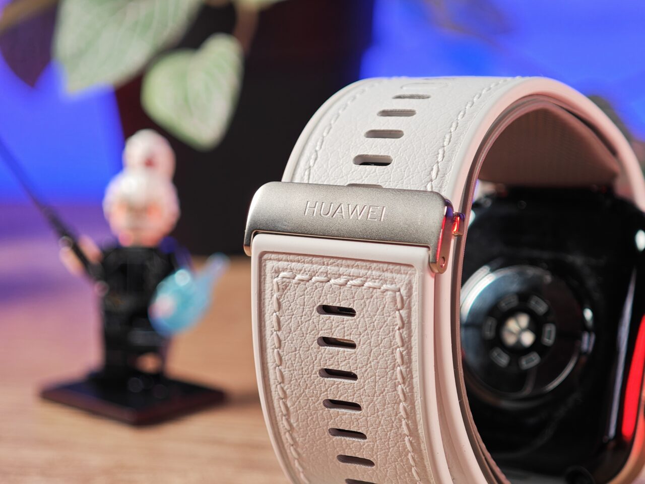 Biały pasek zegarka Huawei Watch D2 na zbliżeniu, w tle rozmyta figurka Lego.