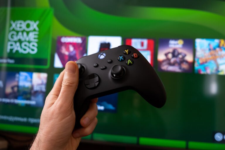 Ręka trzymająca kontroler Xbox na tle ekranu z menu Xbox Game Pass.