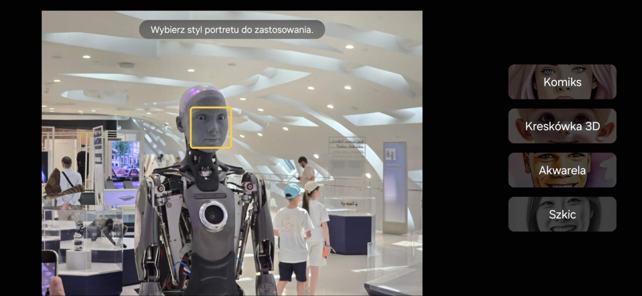 Test AI w Samsung One UI 6.1.1. Robot humanoidalny w nowoczesnym budynku z żółtą ramką na twarzy, na ekranie wybór styli portretów: Komiks, Kreskówka 3D, Akwarela, Szkic.