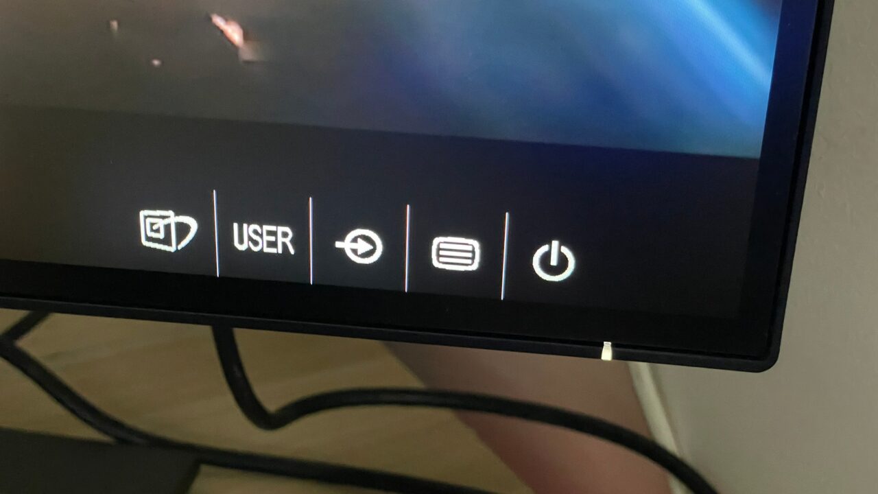 Panel kontrolny monitora z przyciskami funkcyjnymi, w tym zasilanie, menu i przycisk użytkownika.