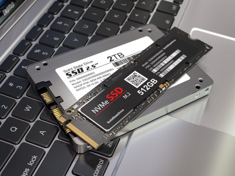 Dwa dyski SSD, jeden 2,5-calowy 2TB i jeden M.2 NVMe 512GB, leżące na klawiaturze laptopa.