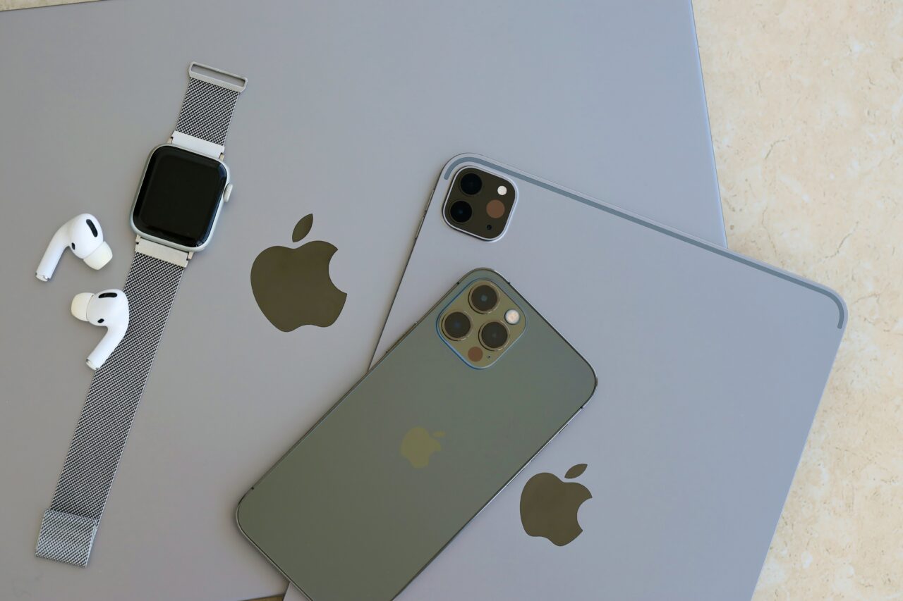 Apple Watch, słuchawki AirPods, iPhone 12 Pro oraz dwa iPady na jasnym tle.