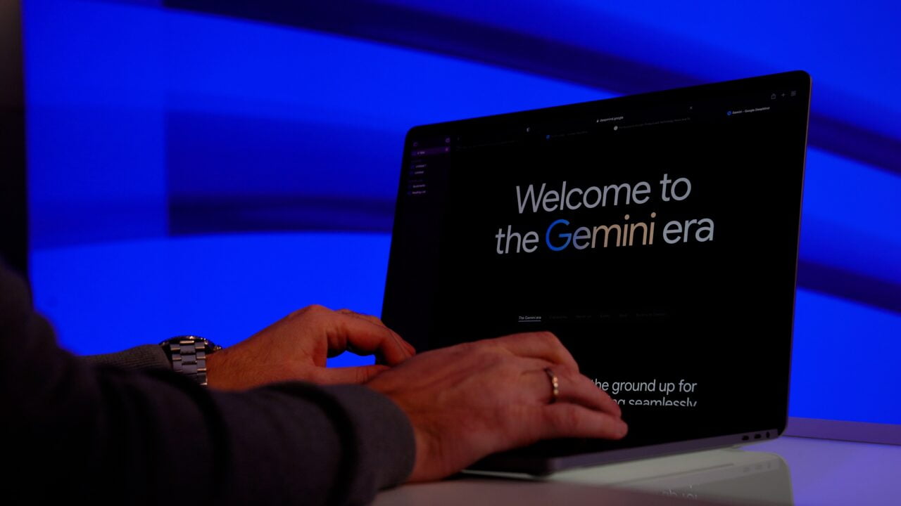 Osoba pisząca na laptopie z widocznym napisem "Welcome to the Gemini era" na ekranie.