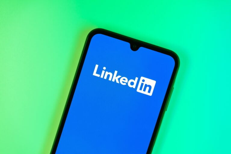 Logo LinkedIn na ekranie telefonu komórkowego na zielonym tle.