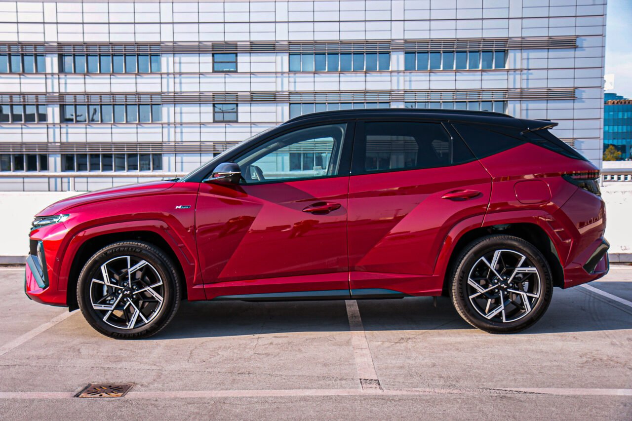 Test Hyundai Tucson Hybrid FL 2024, czerwony samochód hybrydowy na parkingu.