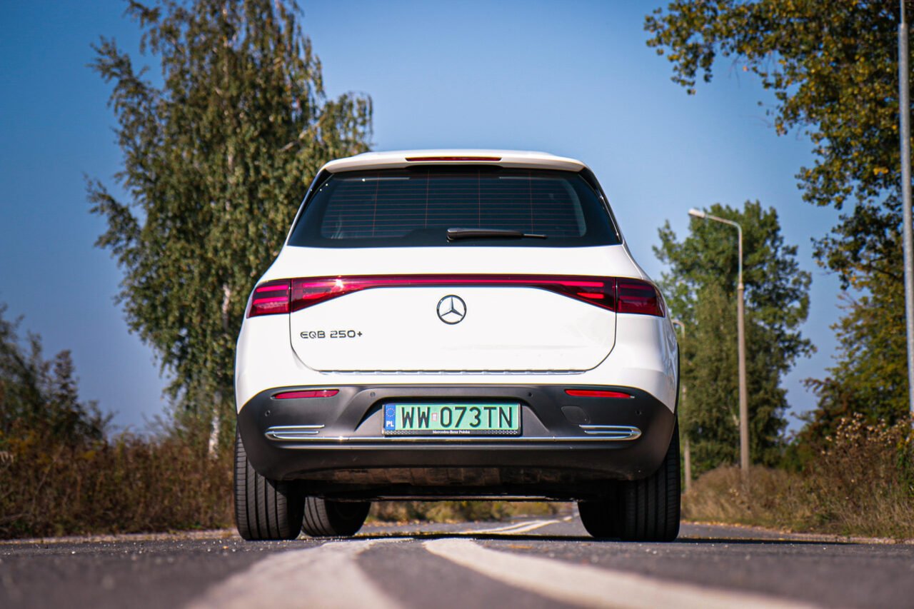 Biały Mercedes EQB 250+ sfotografowany z tyłu podczas testu na wiejskiej drodze.