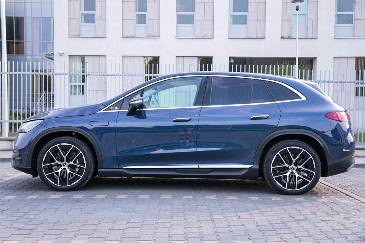 Mercedes EQE SUV 500 4MATIC w kolorze granatowym, zaparkowany na tle nowoczesnego budynku.